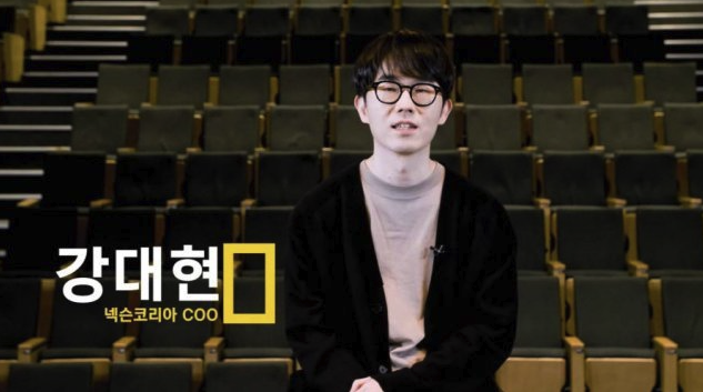 인터뷰 영상 캡처. 빈 강당 객석을 배경으로 안경을 쓴 남성이 이야기하고 있고, 화면 왼쪽 아래에 '강대현 / 넥슨코리아 COO' 자막이 떠 있다.