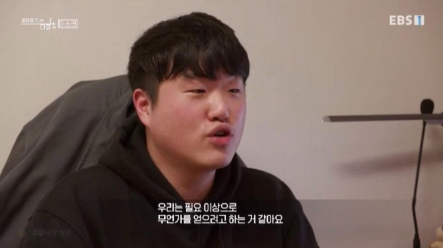 EBS 방송에 인터뷰이로 나온 화면 캡처. 검은 후드를 입고 앉아 이야기하는 내 모습 아래에 "우리는 필요 이상으로 무언가를 얻으려고 하는 거 같아요"라는 자막이 떠 있다.